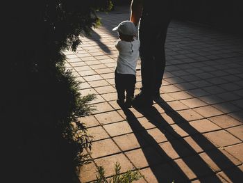 Low section of father standing with son on footpath