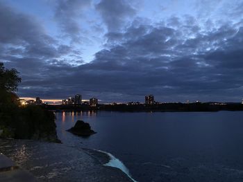 River by buildings against sky at dusk