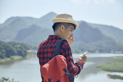 Man wearing hat standing against mountain