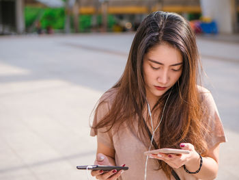 Portrait of beautiful young woman using phone on street
