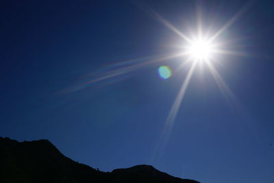 Low angle view of silhouette moon against blue sky