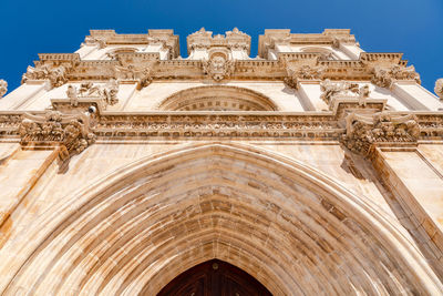 Low angle view of front facade of alcobaca monastery church against a blue sky, portugal