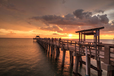 Pier over sea against sky during sunset