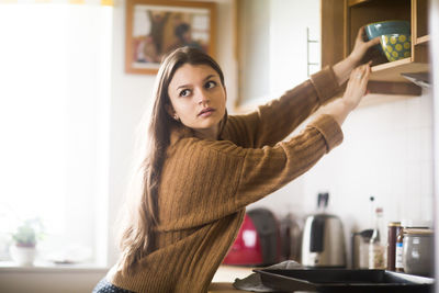 Young woman getting bowl in the kitchen