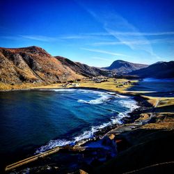 Scenic view of sea and mountains against blue sky