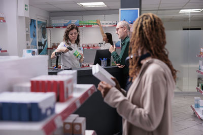 Rear view of woman using mobile phone while standing in office