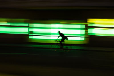 Blurred motion of man riding bicycle on street at night