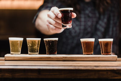 Close-up of hand holding beer glass on table