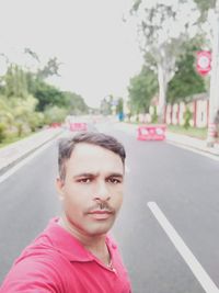Portrait of man standing on road in city