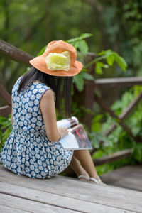 Rear view of woman reading magazine at park