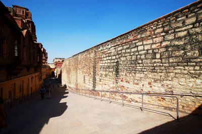 Walkway by fortified wall at mehrangarh fort against clear blue sky