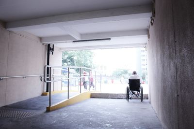 Rear view of handicapped man sitting in wheelchair in building