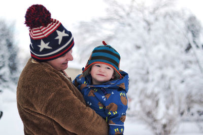 Boy wearing hat against trees during winter