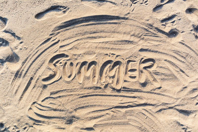 High angle view of text on sand