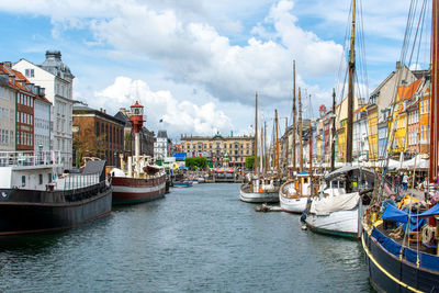 Sailboats moored on harbor in city against sky