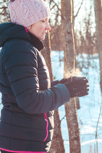 Woman with hot drink in winter forest