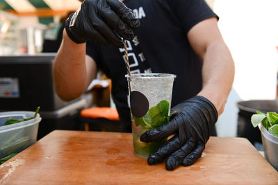 Midsection of man holding lemonade on table in cafe