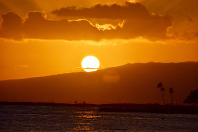 Scenic view of sea and silhouette mountain against sky during sunset