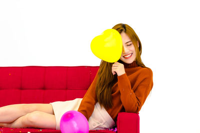 Smiling young woman with balloons against white background