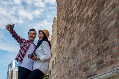 Full length of young man photographing while standing on wall