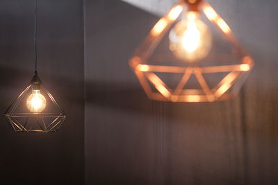 Close-up of illuminated light bulb hanging on wall