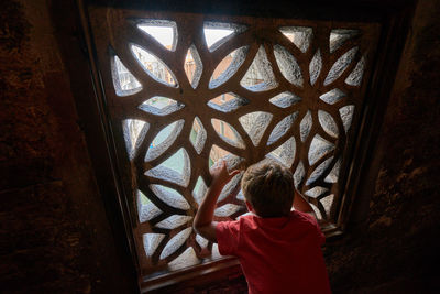 Rear view of boy standing by window