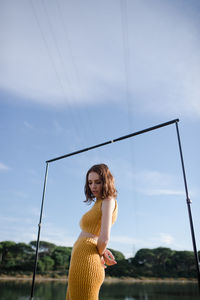 Portrait of smiling young woman standing against sky