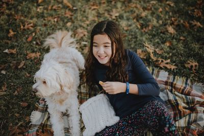 Portrait of smiling woman with dog sitting outdoors