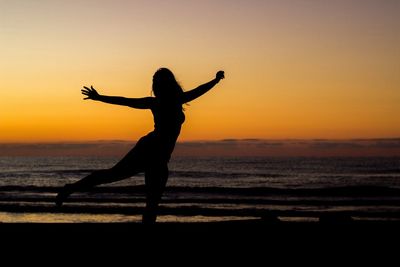 Silhouette person on beach against sky during sunset