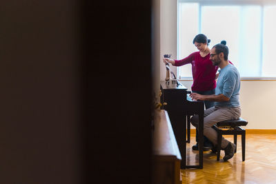 Man and woman using piano at home