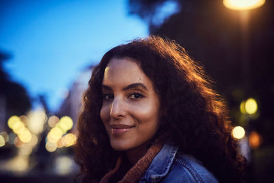 Close-up portrait of smiling young woman in city at night