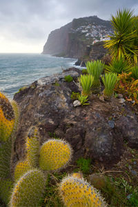 Scenic view of sea by mountain against sky during sunset