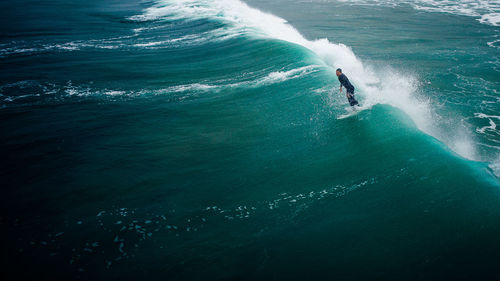 Aerial view of man surfing on waves in sea