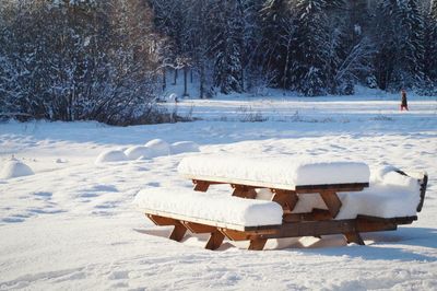 Snow covered wooden picnic table on field