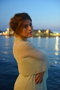 Side view of young woman standing in sea against sky