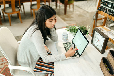 Side view female making purchase with plastic card for order during online shopping via laptop