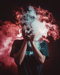 Midsection of man smoking against black background