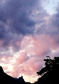 Low angle view of silhouette trees against dramatic sky