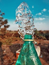 Close-up of glass bottle against blue sky