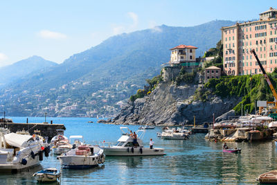 Boats in sea by buildings against sky