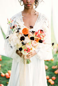 Midsection of bride holding bouquet