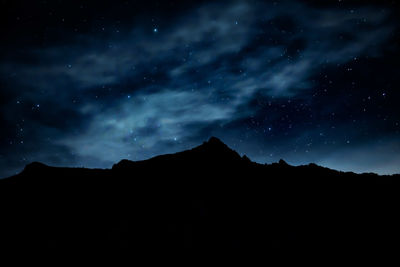 Low angle view of silhouette mountain against sky at night