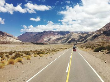 Road leading towards mountains against sky