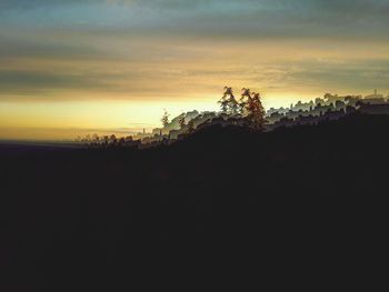Silhouette trees on landscape against sky during sunset