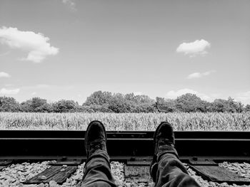 Low section of man sitting on railroad track