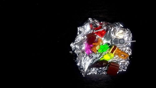 High angle view of multi colored candies against black background