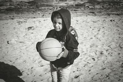 Girl playing with ball on sand at beach