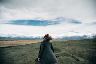 Rear view of woman standing on land against sky