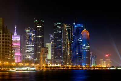 Illuminated buildings in city against sky at night