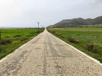 Road amidst field against sky